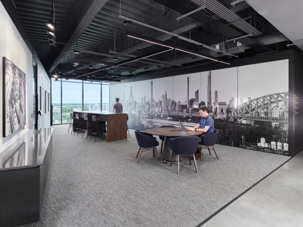 Modern open office with exposed ceiling, collaborative workstations, and branded wall graphics